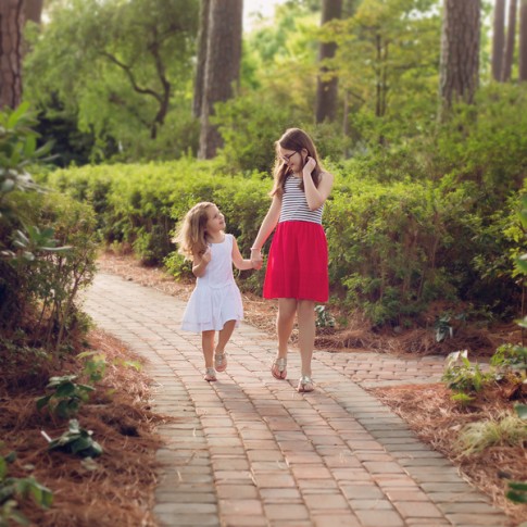 Two sisters walking hand in hand through garden
