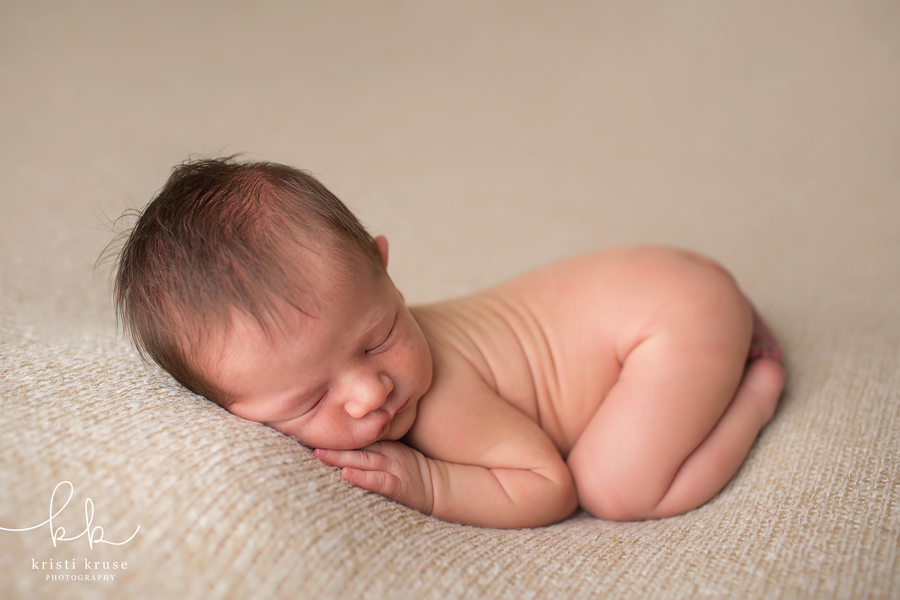 newborn baby boy laying on beige blanket