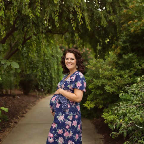Expectant mother in floral dress laying hand on belly