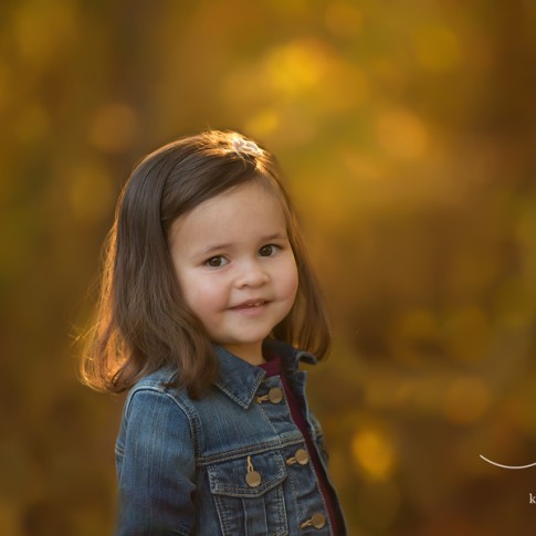 2 year old girl in jean jacket with golden sunlight in her hair
